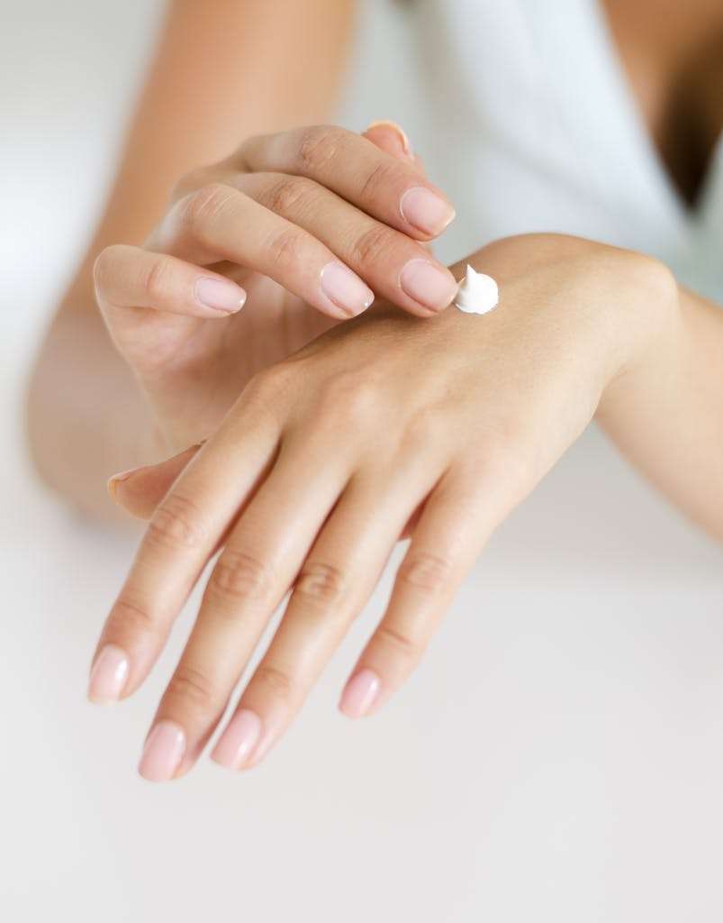 A woman applying cream on her hands, highlighting skincare and self-care concepts.