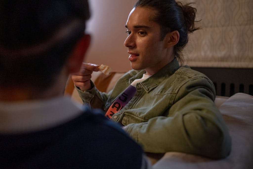 Two friends enjoying a casual conversation indoors, relaxed on a couch.